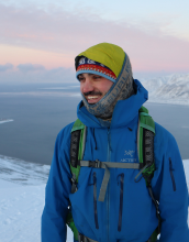 Man in hiking gear with a hat and blue jacket.